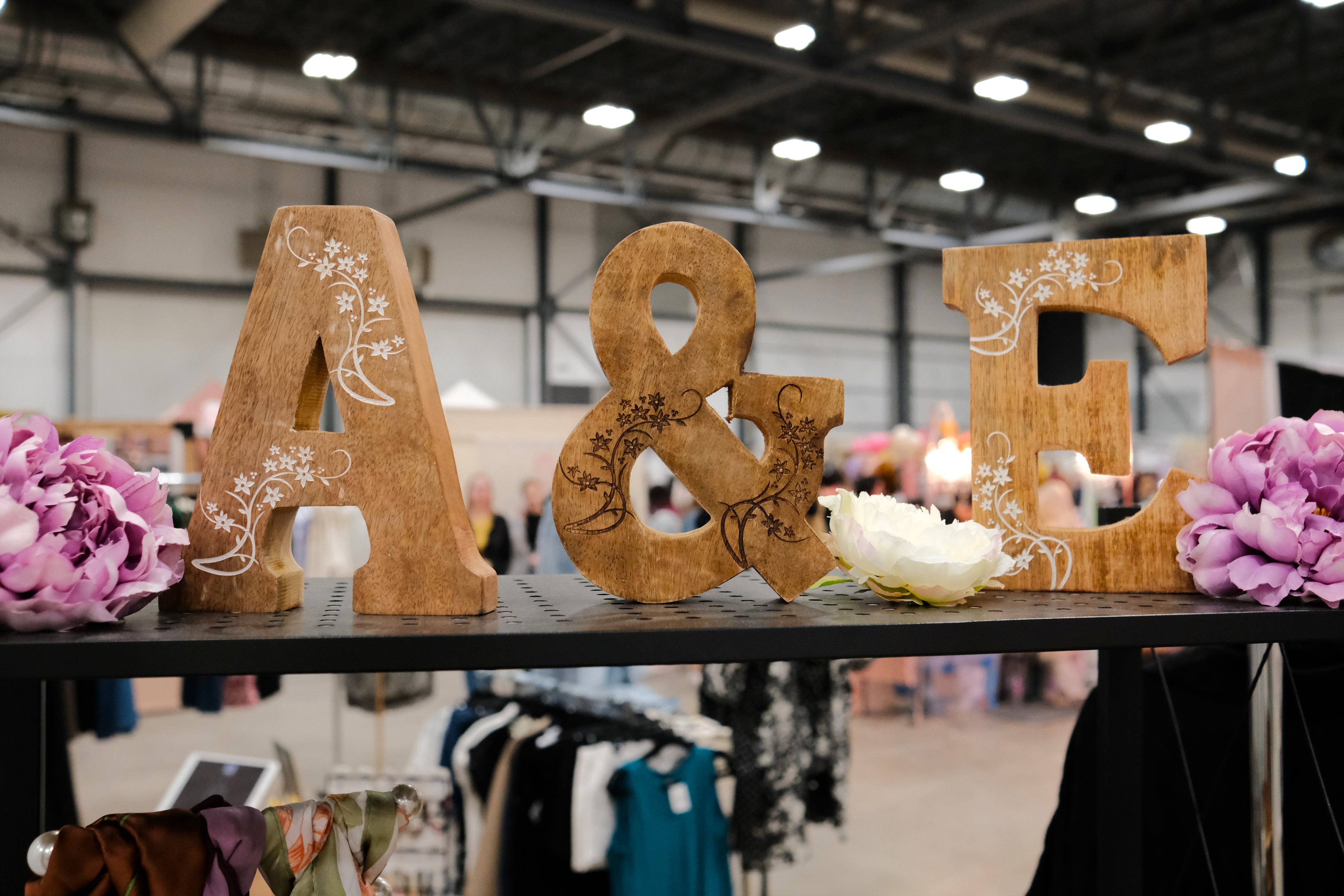 Wooden A and E letters spelling Auds and Ends Boutique, styled with flowers.