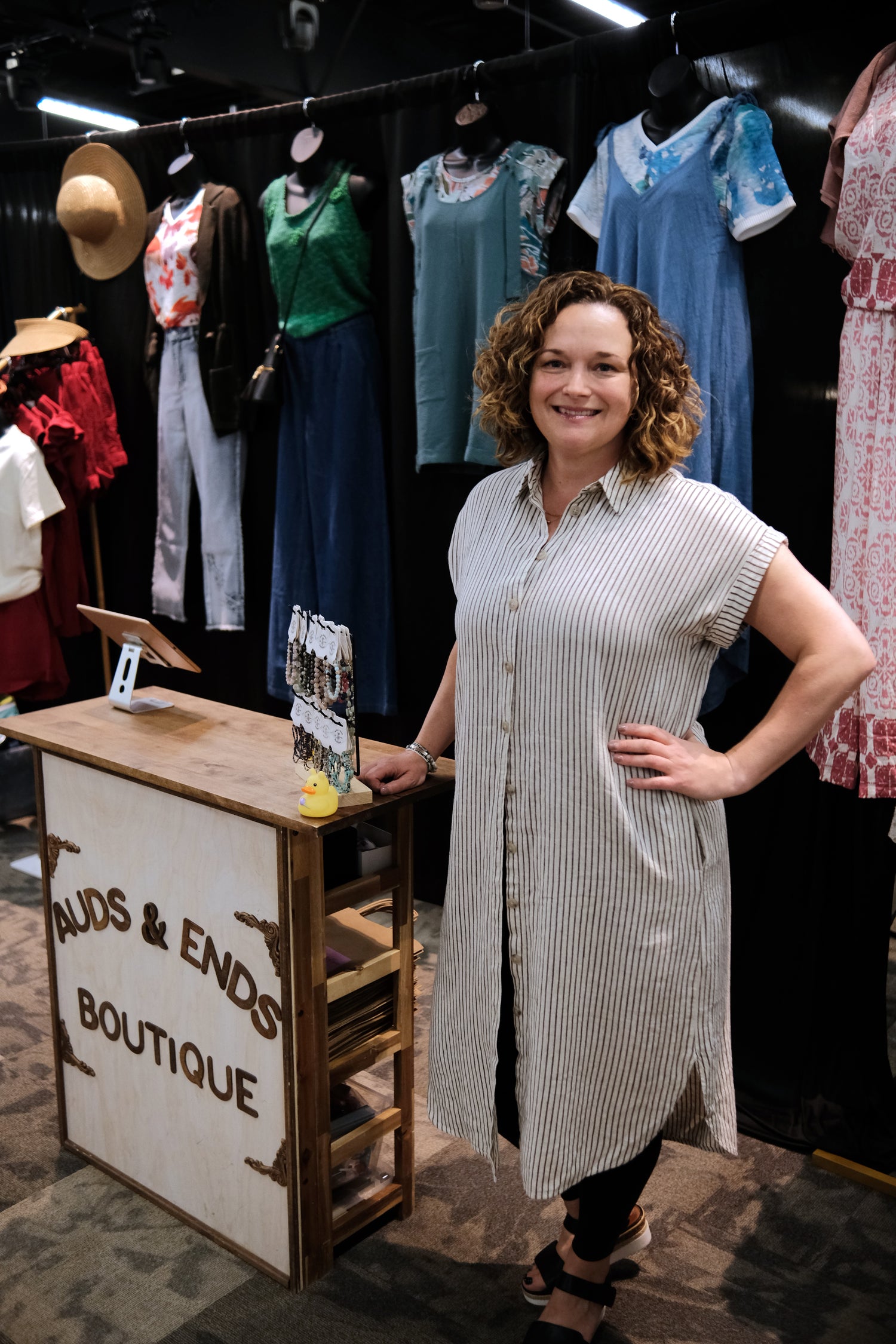 Audrey from Auds & Ends Boutique at a Saskatchewan market, displaying women's clothing in real sizes XS to 2/3X