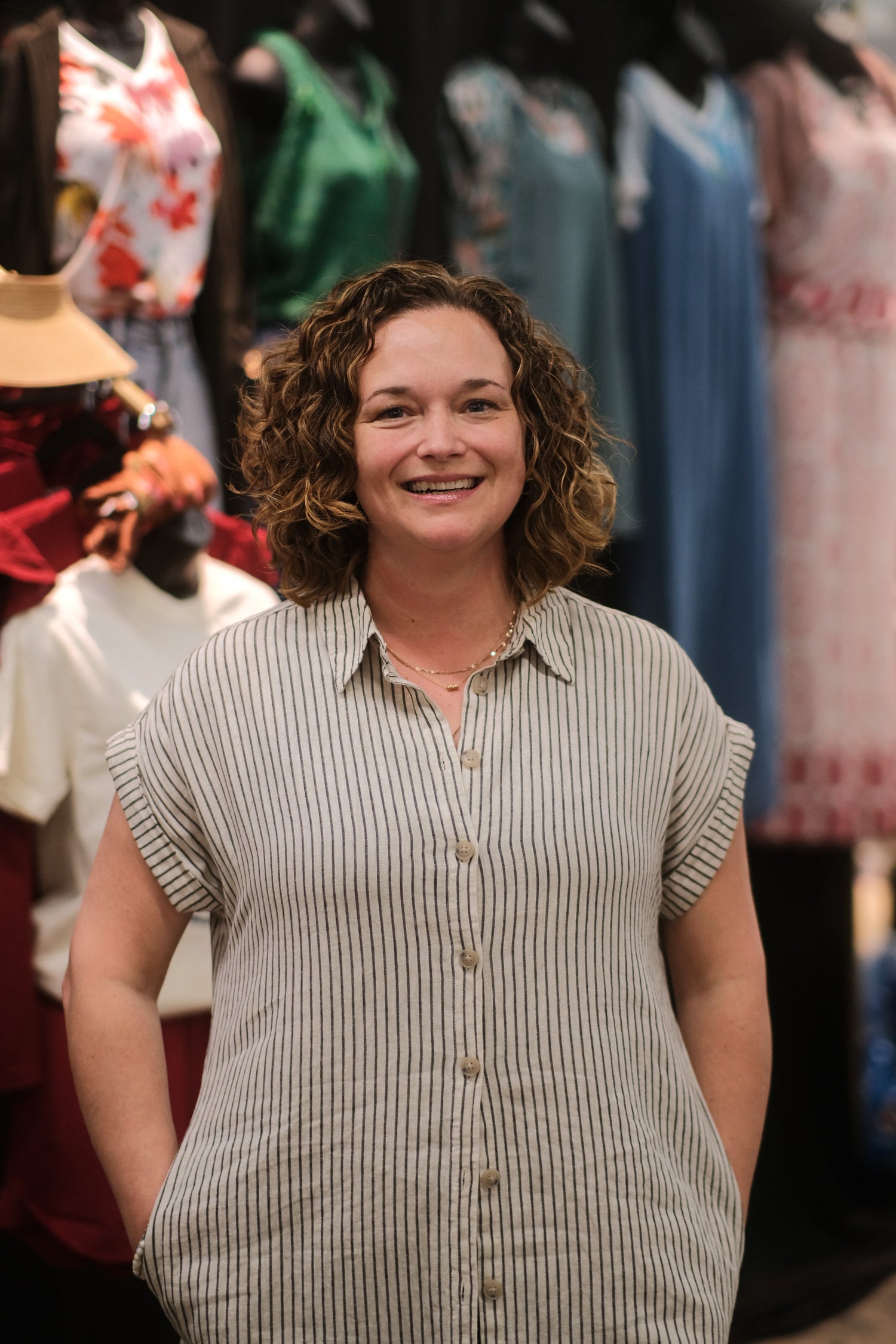 Audrey, owner of Auds & Ends Boutique, standing in front of her market display of women's clothing in real sizes